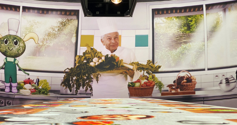 Régis Marcon en scène avec la mascotte Anicia dans une projection immersive